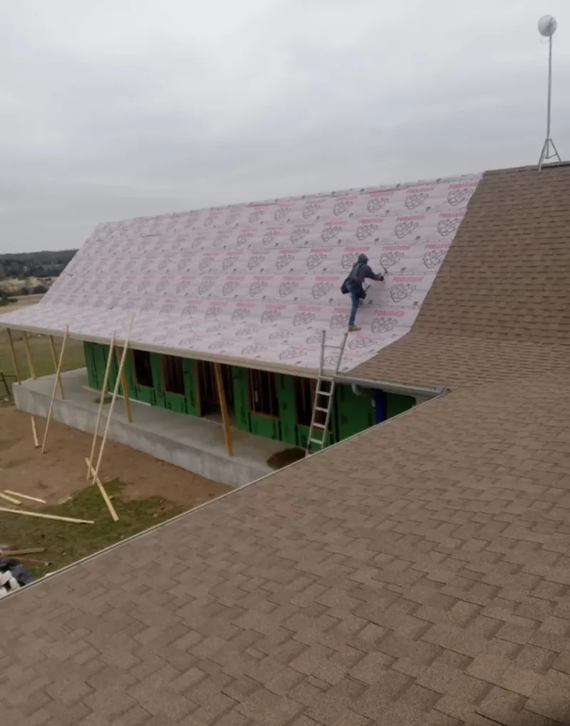 Worker preparing underlayment for a metal roof installation in Midlothian